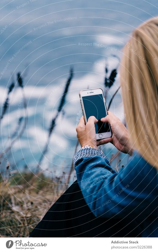 Touristin fotografiert Meer in der Dämmerung Frau Meereslandschaft fotografierend Smartphone Sonnenuntergang Tourismus Horizont Küste malerisch genießen