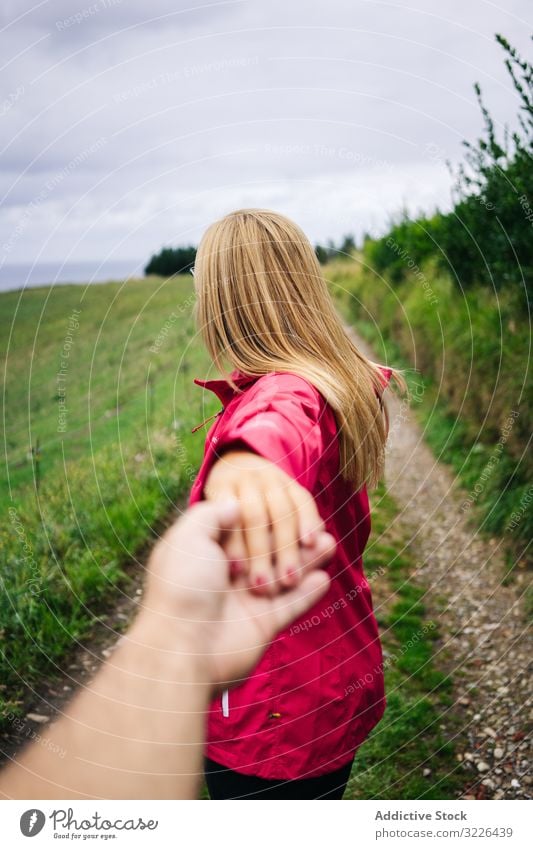 Frau hält Hand des Erntehelfers, der zum Folgen auf die grüne Wiese einlädt mir folgen Landschaft Straße Feld Weg genießend Fundstück strecken Natur Erkundung