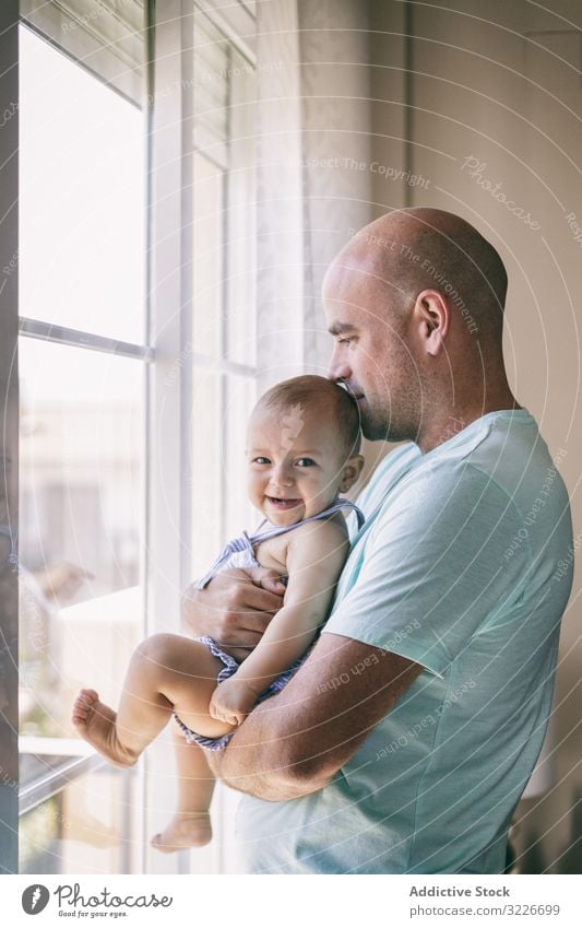 Vater mit Baby, der aus dem Fenster schaut Umarmung Kuss Glück gemütlich heimwärts Raum Familie Mann Kind Kleinkind Eltern Zusammensein Liebe Umarmen Pflege