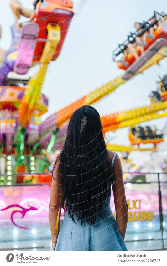 Frau beobachtet sich drehendes Karussell im Vergnügungspark beobachtend Vergnügen Park Starrer Blick Kontemplation Anziehungskraft hell bunt fesselnd