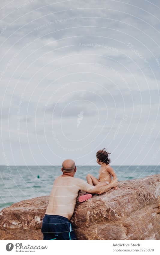 Alter Mann hält kleines Mädchen am steinigen Strand Großvater Enkelin fürsorglich Meer Urlaub Familie Angebot umarmend älter Kind Wasser Natur Ufer genießend