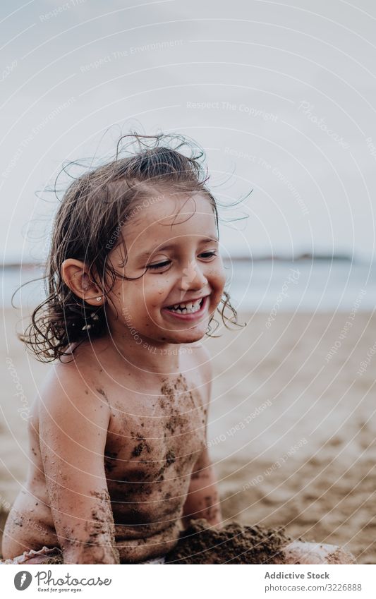 Inspiriertes Kind spielt mit Sand am Strand spielen Sommer Urlaub beschmiert Schürfen Feiertag Spaß Spielen Mund Mädchen Genuss Ausdruck Aktivität heiter