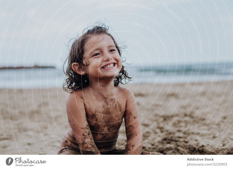 Inspiriertes Kind spielt mit Sand am Strand spielen Sommer Urlaub beschmiert Schürfen Feiertag Spaß Spielen Mund Mädchen Genuss Ausdruck Aktivität heiter