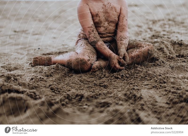 Inspiriertes Kind spielt mit Sand am Strand spielen Sommer Urlaub beschmiert Schürfen Feiertag Spaß Spielen Mund Mädchen Genuss Ausdruck Aktivität heiter