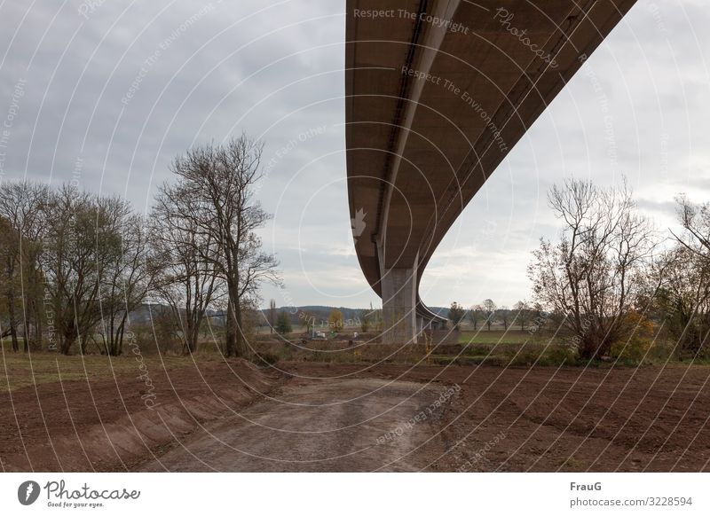 Architektur und Natur| Brückenschwung Autobahn Autobahnbrücke Kurve schwungvoll Hochstraße Beton Verkehrswege Bauwerk Baustelle Bäume Feld Erde Herbst Himmel