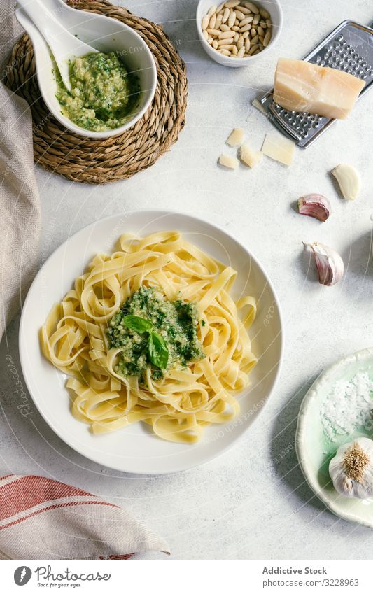 Servierter Teller mit Pesto-Nudeln neben einer Schüssel mit Sauce auf dem Tisch Spätzle Saucen Küche frisch gekocht weiß Knoblauch Erdöl Basilikum Tagliatelle