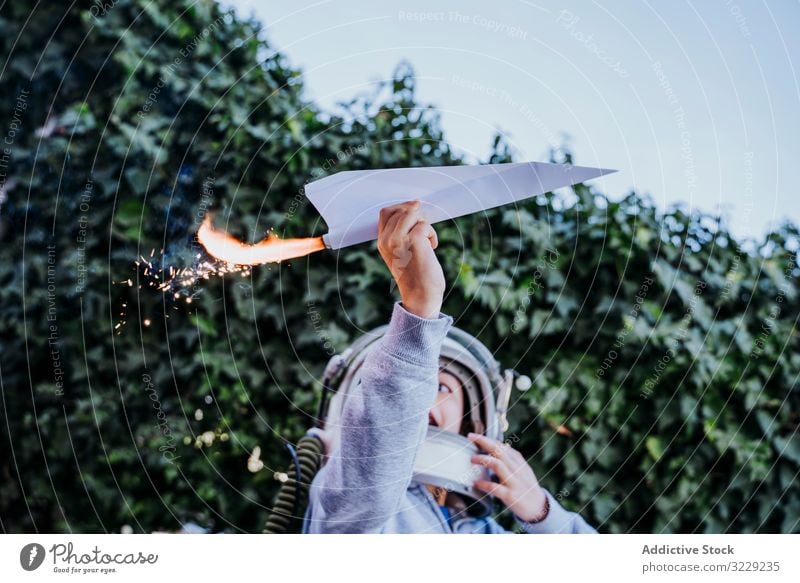 Überraschtes Kind hat Spaß mit funkelndem Flugzeug Junge spielen Ebene Spielzeug aufgeregt Papier petard überrascht Astronaut Schutzhelm Garten Glück Kindheit