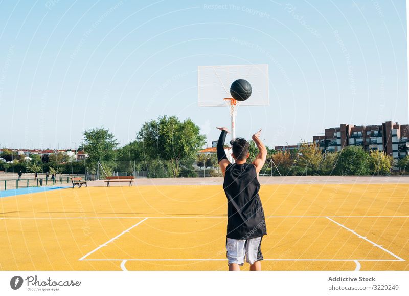 Junger Mann spielt auf gelbem Basketballfeld im Freien. Athlet Konkurrenz Sportgerät Erwachsener Erholung Aktion Ball Porträt aktiv Aktivität Asphalt sportlich