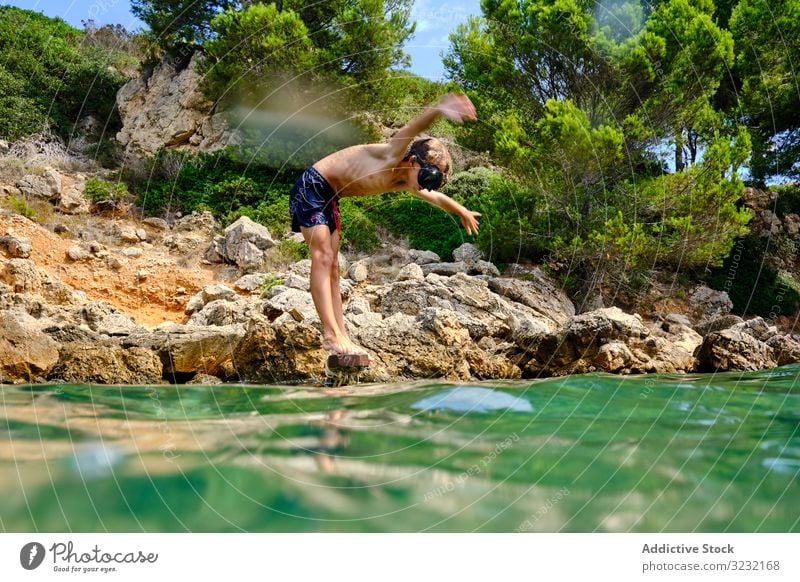 Kleiner Junge macht sich bereit, ins Wasser zu springen MEER Sinkflug Sommer Meeresufer Gleichgewicht Kind Mundschutz Küste reisen aktiv felsig Tourismus Klippe