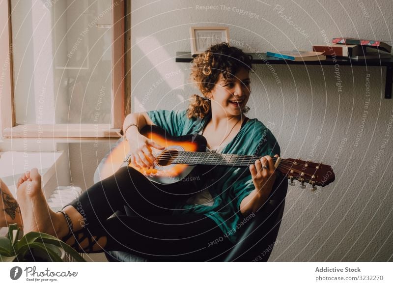 Zufriedene Frau spielt zu Hause Gitarre spielen Inhalt entspannt lässig Barfuß akustisch minimalistisch Raum heimwärts Stock sitzen Musiker Gitarrenspieler