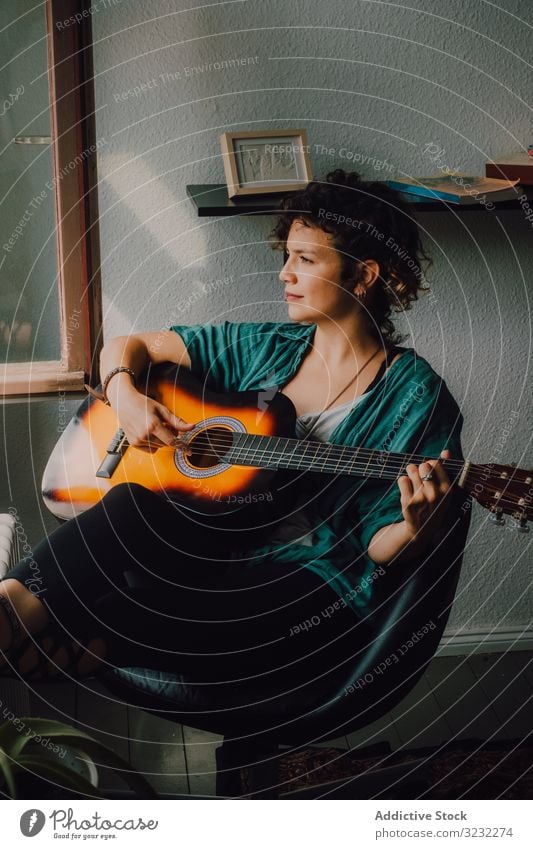 Zufriedene Frau spielt zu Hause Gitarre spielen Inhalt entspannt lässig Barfuß akustisch minimalistisch Raum heimwärts Stock sitzen Musiker Gitarrenspieler