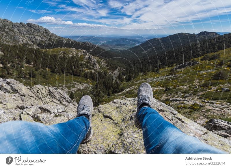 Person sitzt mit baumelnden Beinen auf Stein über dem Bergtal Cloud Himmel Berge u. Gebirge Natur reisen Park Wald Tal Landschaft malerisch Hügel felsig