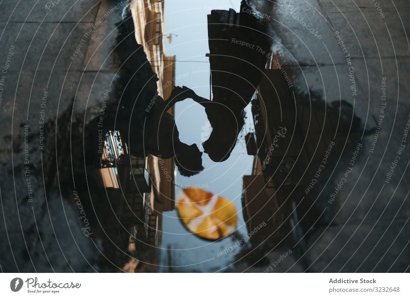 Spiegelung eines sich küssenden Paares in einer Pfütze auf der Straße Kuss Silhouette Reflexion & Spiegelung Wasser Großstadt Regen nass Schatten laufen