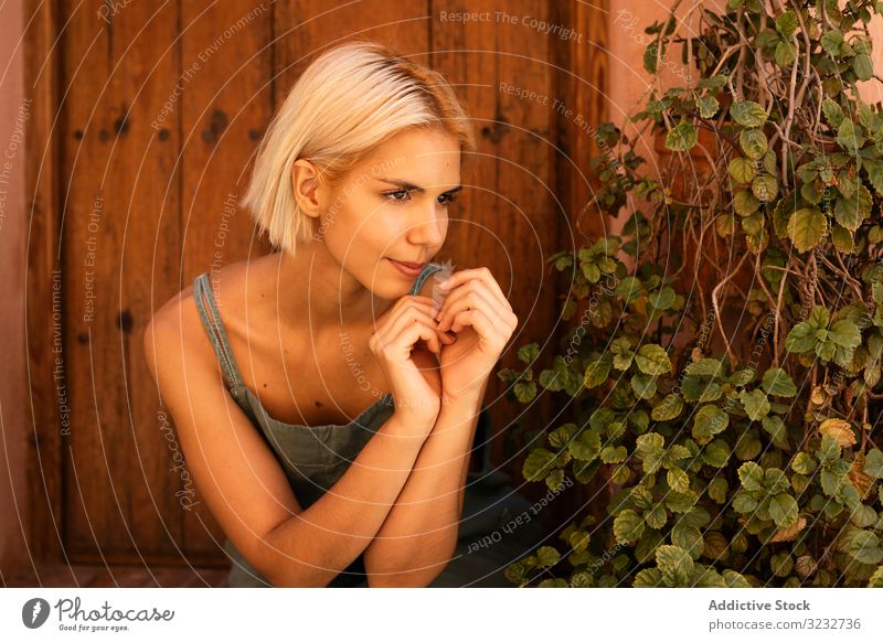 Junge Frau sitzt auf der Türschwelle Pflanze sitzen Hof Garten Vorstadt Flora Wachstum Vegetation jung Gartenbau Anwesen heimwärts gemütlich blond Harmonie