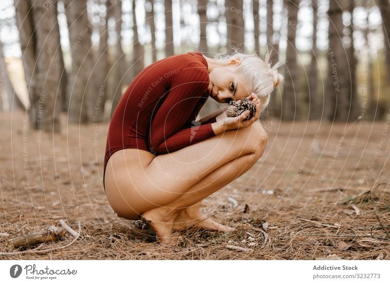 Schöne moderne Frau ruht barfuss in immergrünem Wald Wälder Harmonie hockend primitiv umarmende Knie blond sorgenfrei Barfuß attraktiv schön charmant ruhen