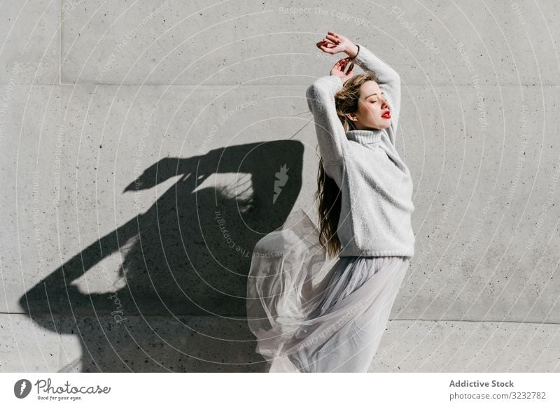 Trendige Dame mit geschlossenen Augen auf der Straße Frau stylisch sinnlich geschlossene Augen lange Haare elegant Wand Gebäude Model sonnig tagsüber jung cool