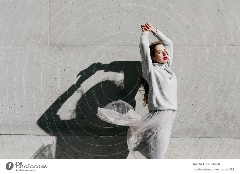 Trendige Dame mit geschlossenen Augen auf der Straße Frau stylisch sinnlich geschlossene Augen lange Haare elegant Wand Gebäude Model sonnig tagsüber jung cool