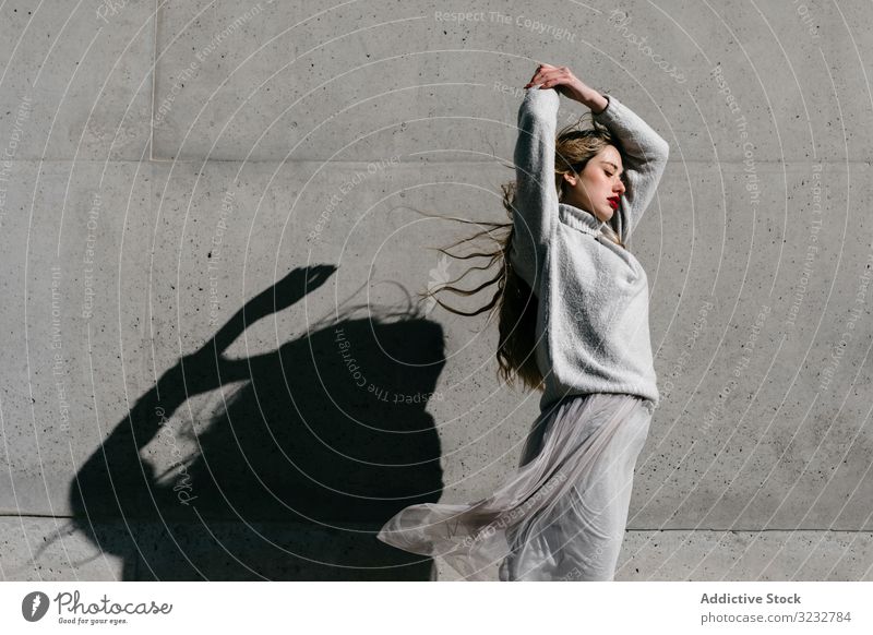 Trendige Dame mit geschlossenen Augen auf der Straße Frau stylisch sinnlich geschlossene Augen lange Haare elegant Wand Gebäude Model sonnig tagsüber jung cool