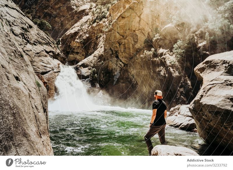 Tourist mit Blick auf Bergwasserfall Wasserfall Berge u. Gebirge Starrer Blick Mann lässig Kontemplation Kaskade felsig Berghang Fluss Nebel Sommer sonnig