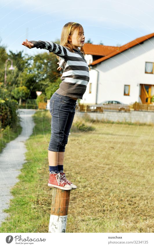 kletterin (geschafft) Kind Mädchen jungennhaft Klettern Spielen gewagt Pfosten Holzpfahl Zaunpfahl Außenaufnahme Fußweg Haus Dorf Gebäude Wohnhaus Natur toben