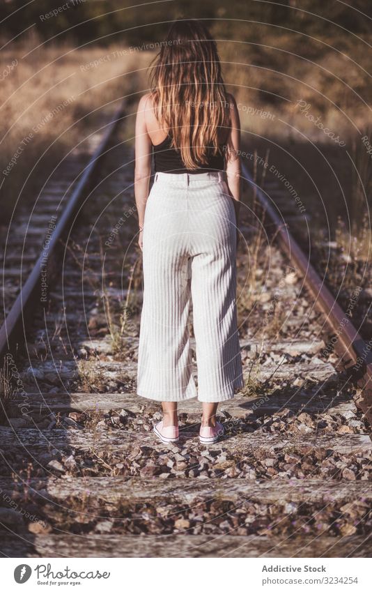 Langhaarige Frau steht auf mit trockenem Gras bewachsenen Eisenbahnen Straße reisen Nostalgie Reise Bahn Weg klassisch Passagier Tourismus Ausflugsziel Station