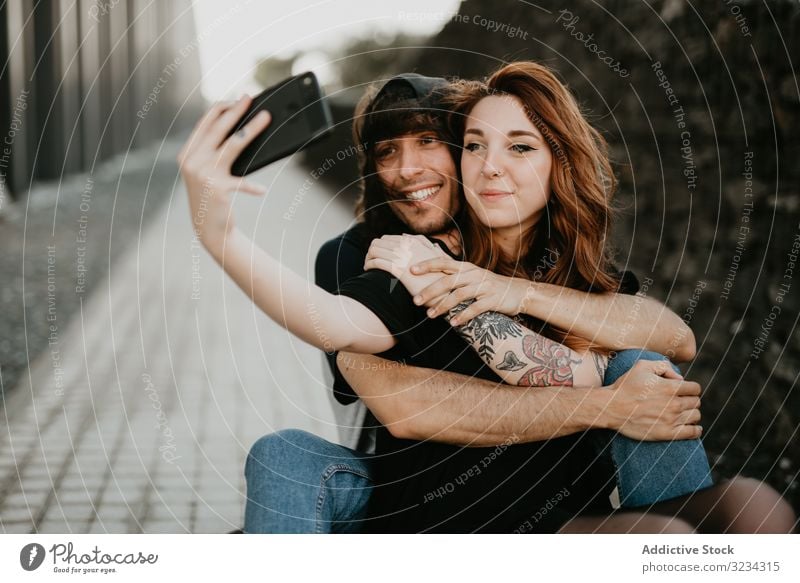 Skater sitzen auf der Straße und nehmen Selfie auf dem Smartphone Paar cool Teenager Skateboard modern urban Liebe Zusammensein Stil Hipster Telefon Tattoo