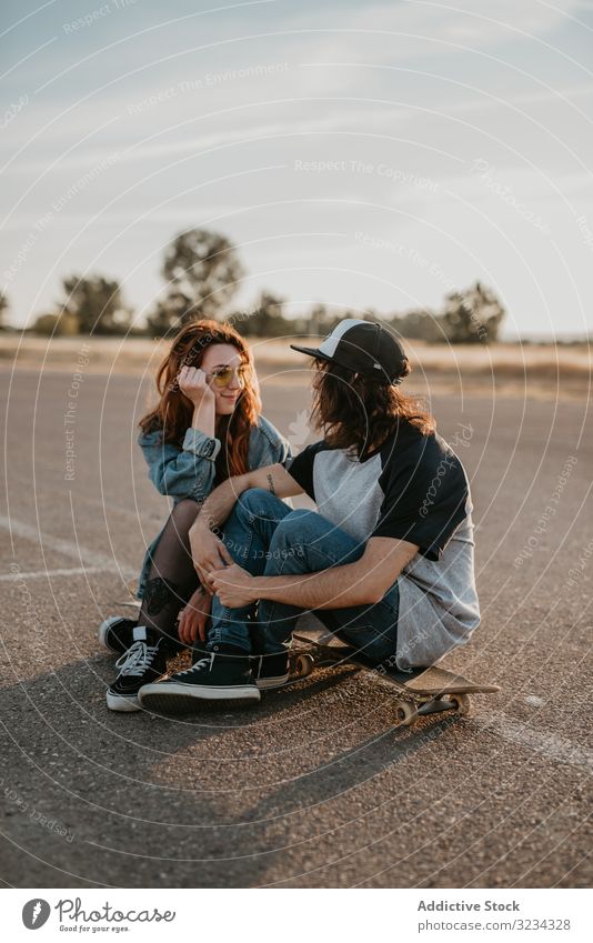 Schlittschuhläufer sitzen auf leerer Landstraße und plaudern im Sonnenlicht Paar Teenager Skater Straße ländlich Zusammensein Generation Sport Landschaft