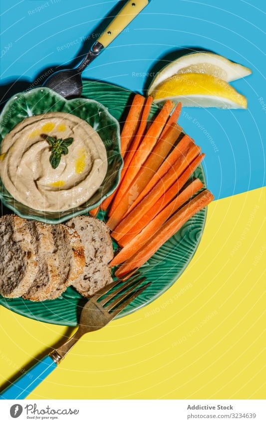 Leckerer gesunder Snack aus Karotten mit Brot und Sauce Amuse-Gueule Dip Möhre Speise Zuprosten Platte Saucen Lebensmittel serviert frisch Hummus Erbse