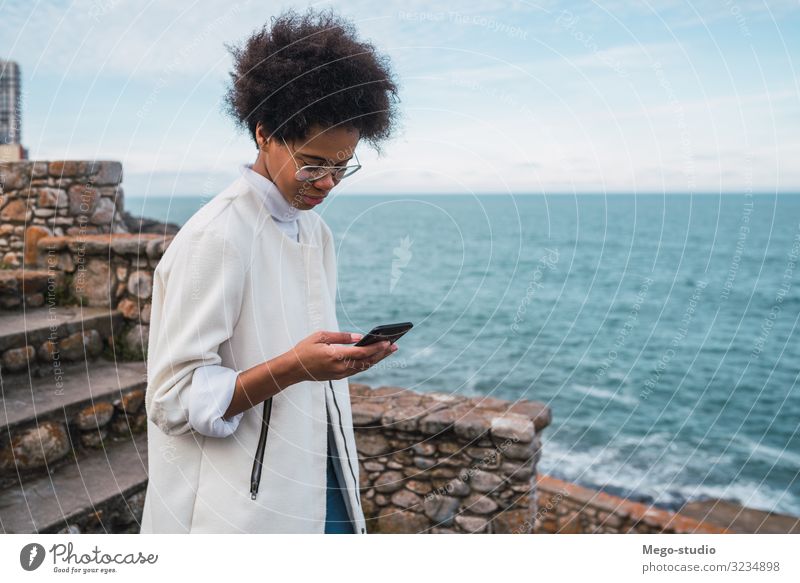 Junge Frau benutzt ihr Mobiltelefon. Lifestyle Freude schön Erholung lesen Meer Dekoration & Verzierung Telefon PDA Technik & Technologie Internet Mensch