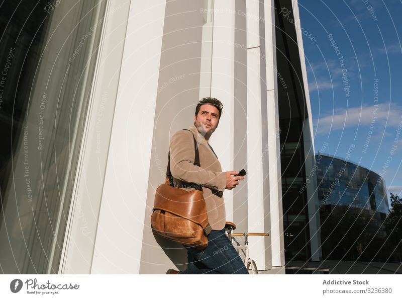 Geschäftsmann mit Smartphone lehnt sich an Gebäude auf Stadtstraße an Großstadt Straße fettarm Wand Stadtzentrum Business männlich professionell Unternehmer