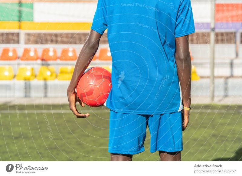 Schwarzer Fussballspieler mit auf dem Stadion stehendem Ball Spieler Fußball Feld Training Sitze Sportbekleidung ethnisch Gras männlich Rasen Netz sonnig