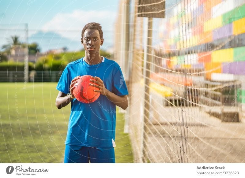 Schwarzer Teenager auf Fussballplatz Fußball Feld fettarm Netz Ball Training Sportbekleidung ethnisch Gras männlich Jugendlicher Rasen sonnig tagsüber schwarz