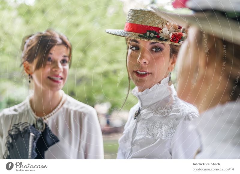 Alte Freundinnen sprechen im Garten Frauen Lächeln reden altehrwürdig Kleid Park Tracht elegant Sommer altmodisch klassisch Talkrunde Gespräch Hut Regenschirm