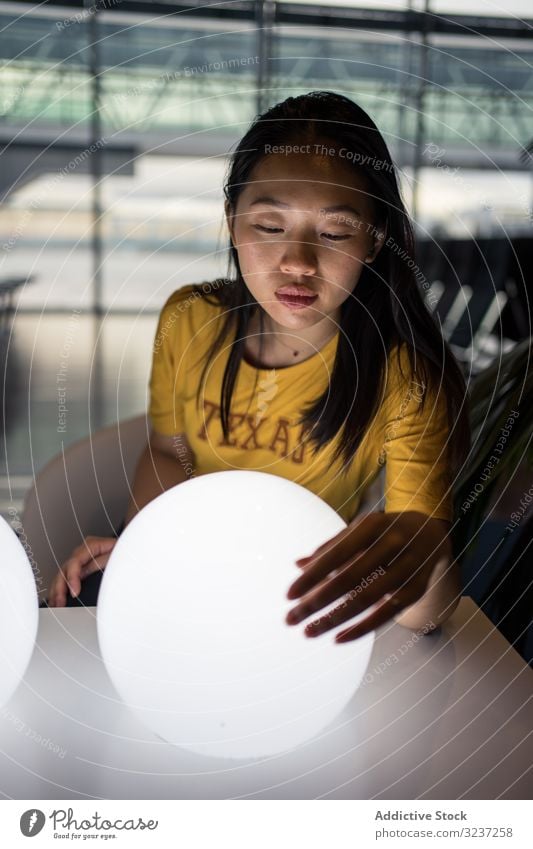 Asiatin untersucht runde Lampen auf dem Tisch Frau Licht kreativ Aufregung Saal beleuchtet Innenbereich asiatisch Kunst Design elektrisch Kraft Glühbirne