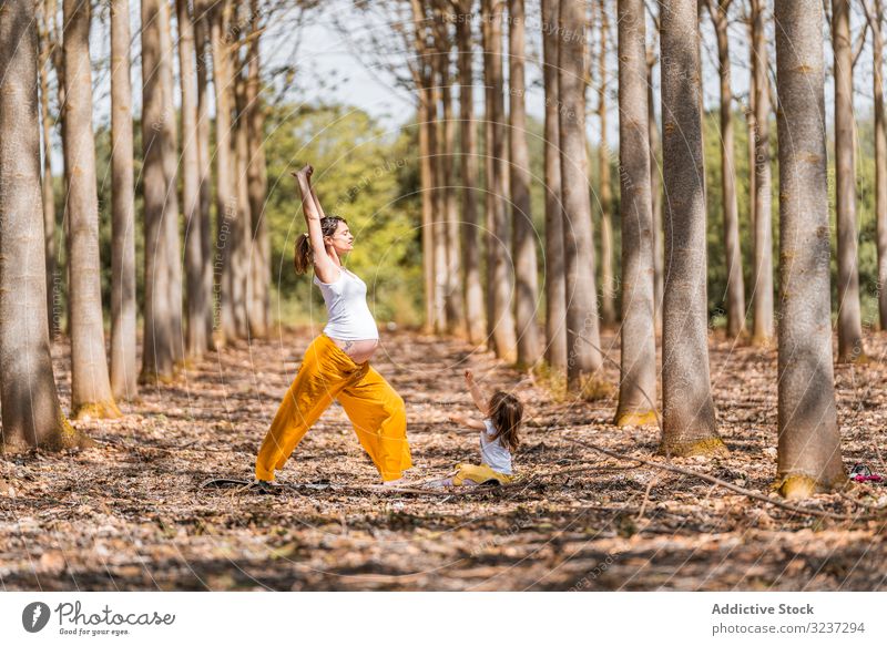 Fröhliche Mutter und Tochter praktizieren bei Sonnenschein Yoga im Park heiter Dehnung Waldwiese sich[Akk] entspannen Spaß üben Übung Lachen Harmonie Pose