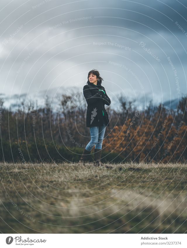 Junge Frau steht im Herbstfeld Feld Land wolkig trist Schnee Hügel Spaziergang Wiese Wald jung allein gefroren kalt Natur Erholung ruhen fröstelnd Reise