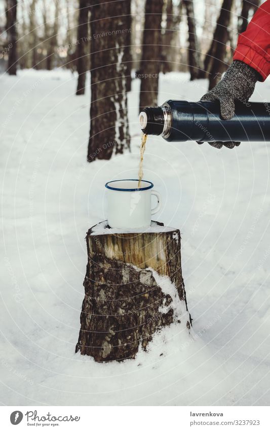 Männerhand, die Heißgetränk in eine Email-Tasse gießt. Thermosflasche Hintergrund Getränk braun Kaffee kalt trinken Wald frisch Handschuhe wandern heiß