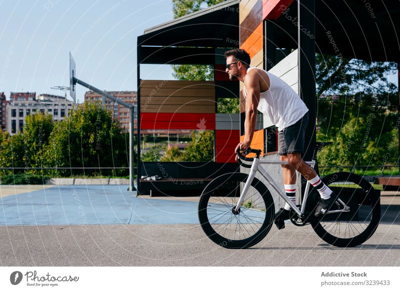 Mann fährt Fahrrad neben Gebäuden Mitfahrgelegenheit Brücke Großstadt modern aktiv sportlich Sommer männlich Sonnenbrille Radfahrer Erholung Gesundheit