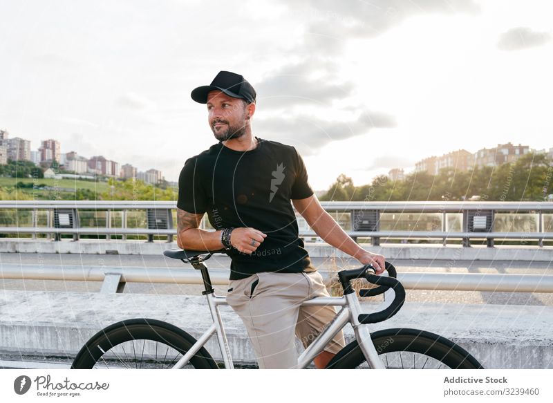 Fröhlicher Mann mit Fahrrad auf Steg stehend Großstadt Mitfahrgelegenheit Brücke modern aktiv sportlich Sommer männlich Erwachsener Glück heiter Lächeln