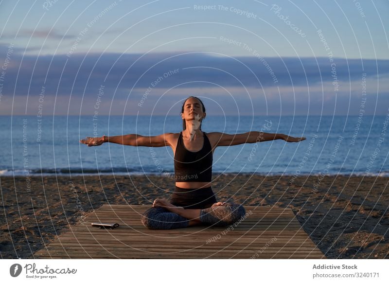 Erwachsene Frau meditiert abends am Meer Yoga MEER Strand Asana Aktivität Abend passen gekreuzte Beine Himmel wolkig positiv Sportbekleidung Training Fitness