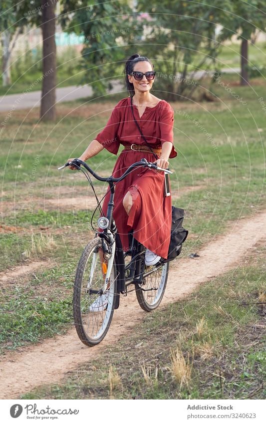 Frau fährt Fahrrad im Park Weg Lächeln lässig Großstadt Sommer Aktivität Fahrzeug Verkehr Lifestyle ruhen sich[Akk] entspannen Wochenende heiter Dame Kleid