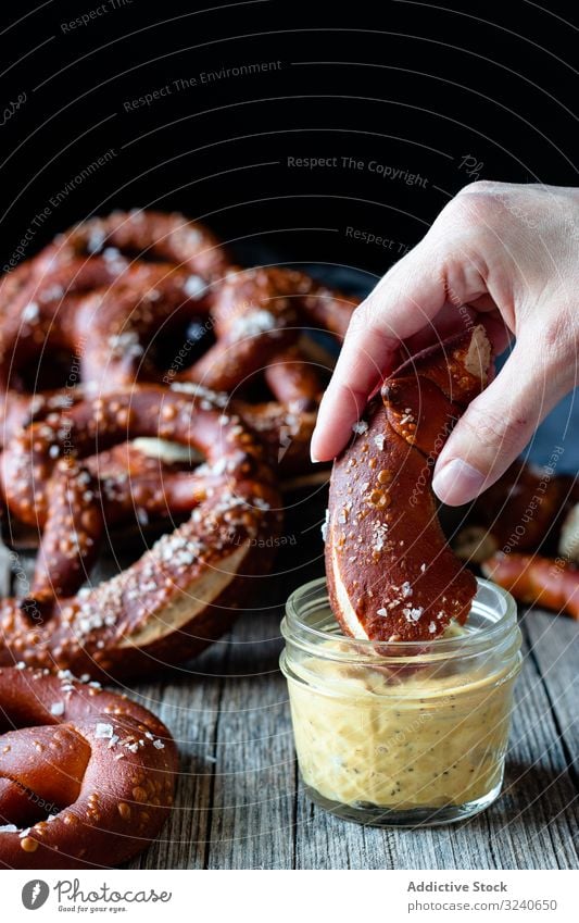 Gesichtslose Person isst köstliche Brezeln Dip Saucen Snack Lebensmittel gesalzen gebacken lecker essen Käse frisch geschmackvoll Deutsch Küche Mahlzeit