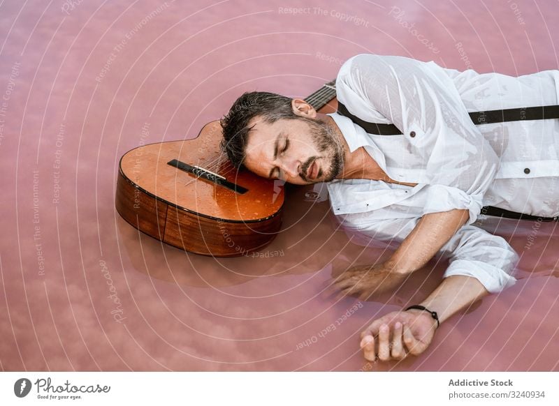 Im Wasser liegender Mann mit Gitarre am Meer ruhen Seeküste stilvoll fliegend MEER Sandbank weißes Hemd Hosenträger verträumt friedlich Windstille neutral jung