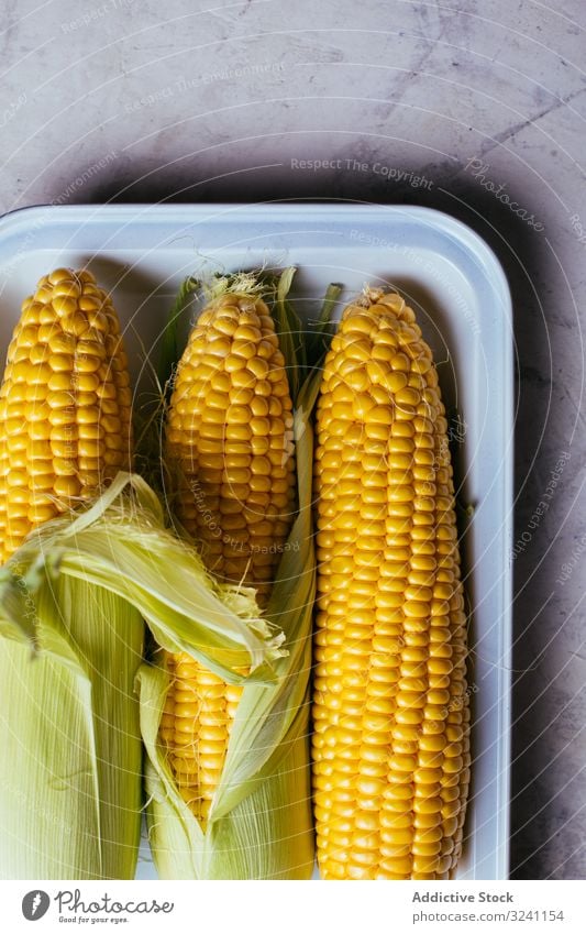 Tablett mit frischem Mais auf dem Tisch sich[Akk] schälen reif Küche Gemüse Lebensmittel Wachstum Ackerbau Natur Murmel Snack Saison Kernel Samen Pflanze