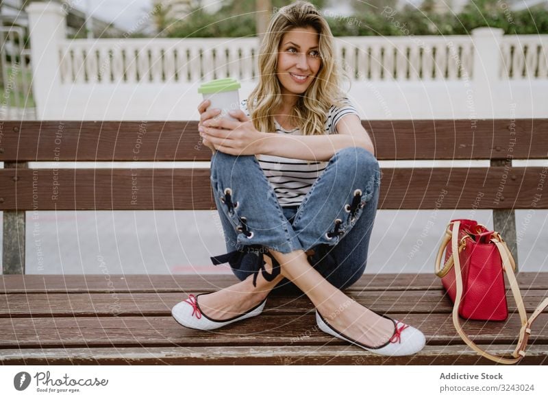 Glückliche Frau mit Einwegkaffee auf Straßenbank sitzend Bank Großstadt Kaffee Strandpromenade freudig genießen lässig ruhen jung Lachen Lächeln aufgeregt schön