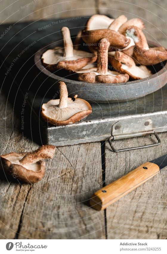 Haufen frischer brauner Champignons auf rustikalem Holztisch Pilz Bestandteil Messer Küche Essen zubereiten Ernährung Shiitake Lebensmittel Mahlzeit kultiviert