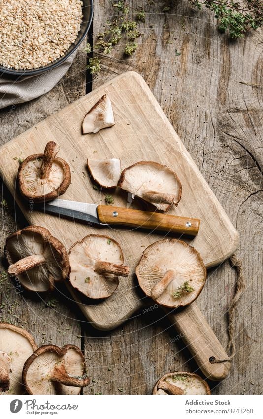 Haufen frischer brauner Champignons auf rustikalem Holztisch Pilz Bestandteil Messer Küche Essen zubereiten Ernährung Shiitake Lebensmittel Mahlzeit kultiviert