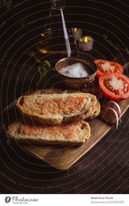 Gewürze und Gemüse in der Nähe von Toast Zuprosten Saucen Bestandteil Tomate Salz Knoblauch Basilikum Erdöl Brot Schneidebrett Tisch Lebensmittel Snack lecker