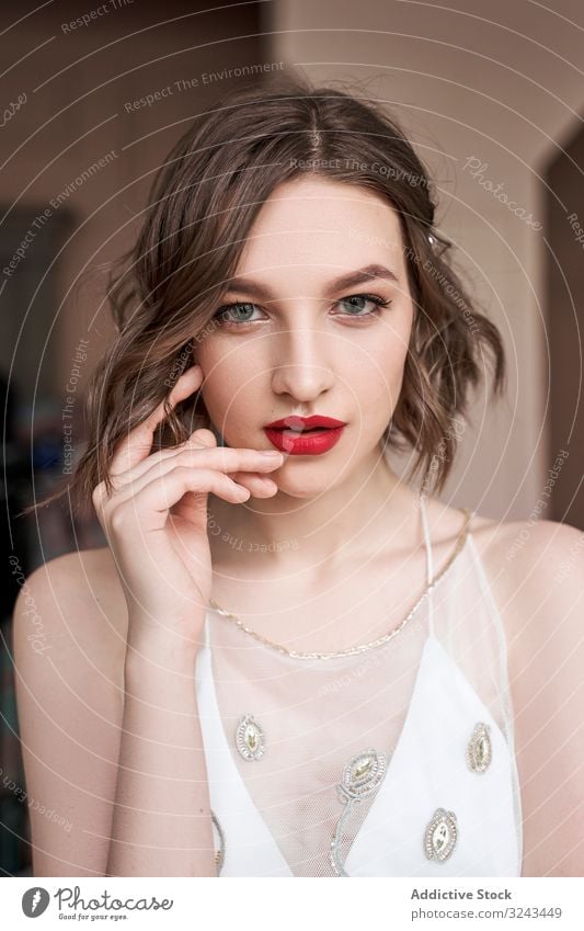 Wunderschöne junge selbstbewusste Frau mit roten Lippen, die in die Kamera schaut weißes Kleid trendy sinnlich Windstille Make-up rote Lippen besinnlich Charme