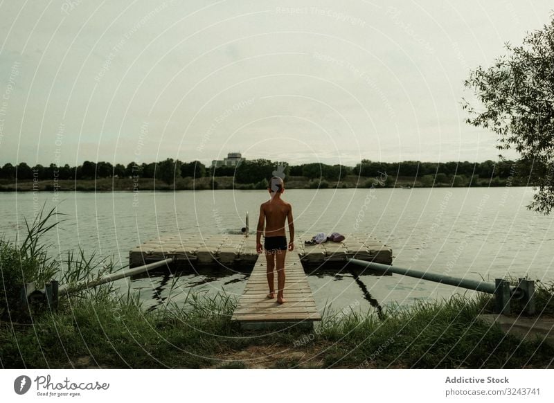 Kind in Badehose geht am Steg entlang zum Wasser Schwimmsport Pier laufen schwimmen Urlaub Harmonie Wochenende Einsamkeit Natur Frieden Windstille ruhen wenig